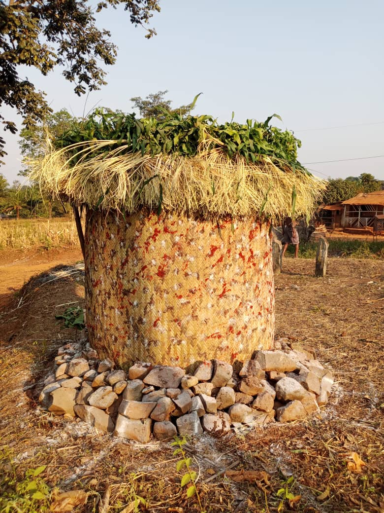 Round painted Nibang-nket hut with stones at base